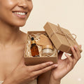 Person holding a gift box with skincare products on a beige background