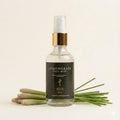 Bottle of Lemongrass Face Mist with lemongrass leaves on a light background