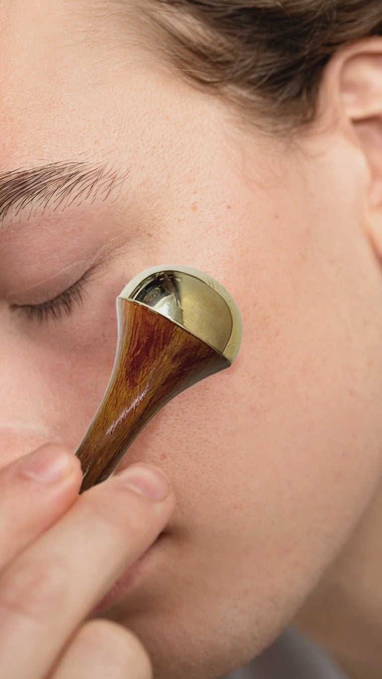 Video of a woman using Kansa Face Massage Wand on her face.